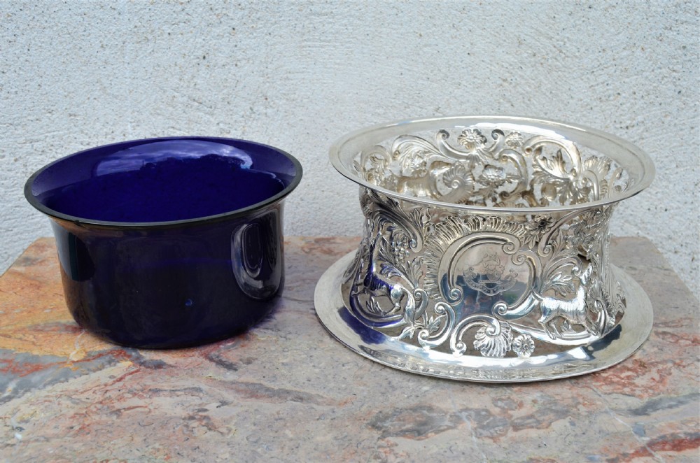 A pierced sterling silver Irish dish ring decorated with repousse animals, scrolls, and an engraved coat of arms, complete with a cobalt blue glass liner. View II