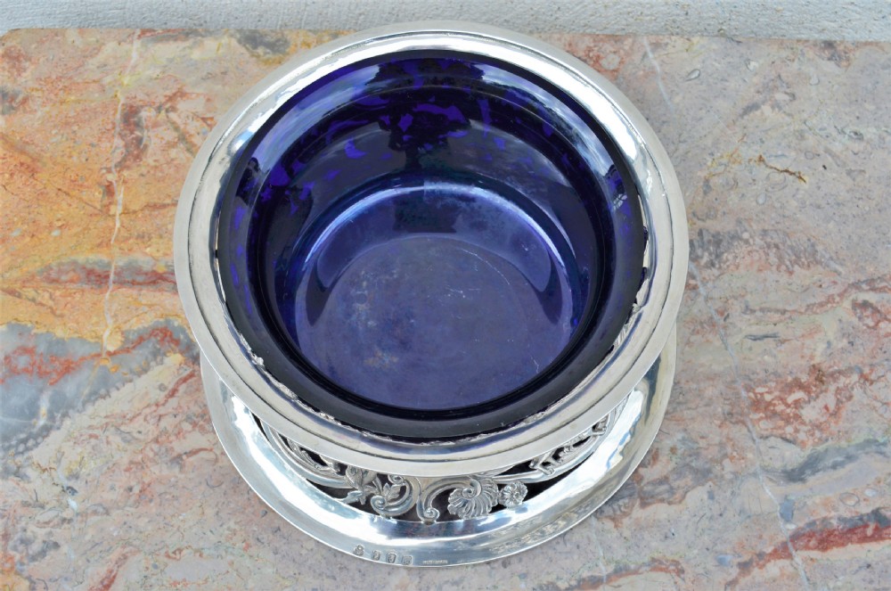 A pierced sterling silver Irish dish ring decorated with repousse animals, scrolls, and an engraved coat of arms, complete with a cobalt blue glass liner. View III