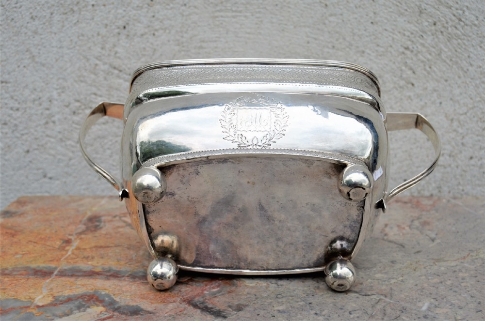 An antique William IV Irish sterling silver basin featuring angular side handles, engraved foliage crest, textured upper band, and ball feet. View III