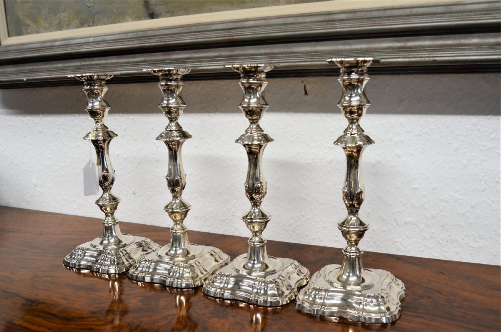 A set of four matching silver candlesticks featuring baluster-shaped stems and moulded square bases arranged side-by-side. View II