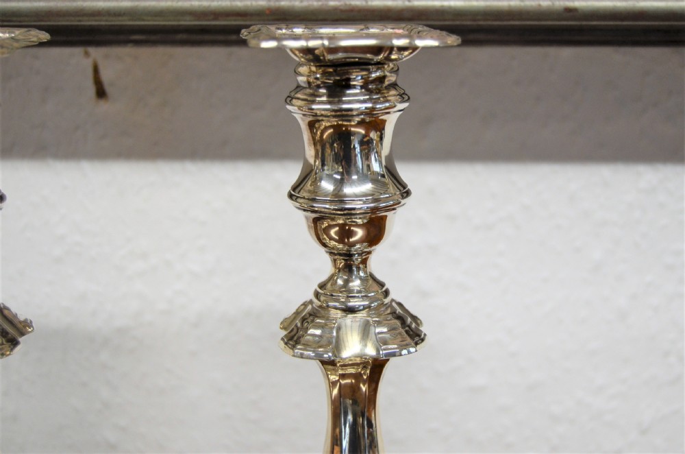 A set of four matching silver candlesticks featuring baluster-shaped stems and moulded square bases arranged side-by-side. View IV