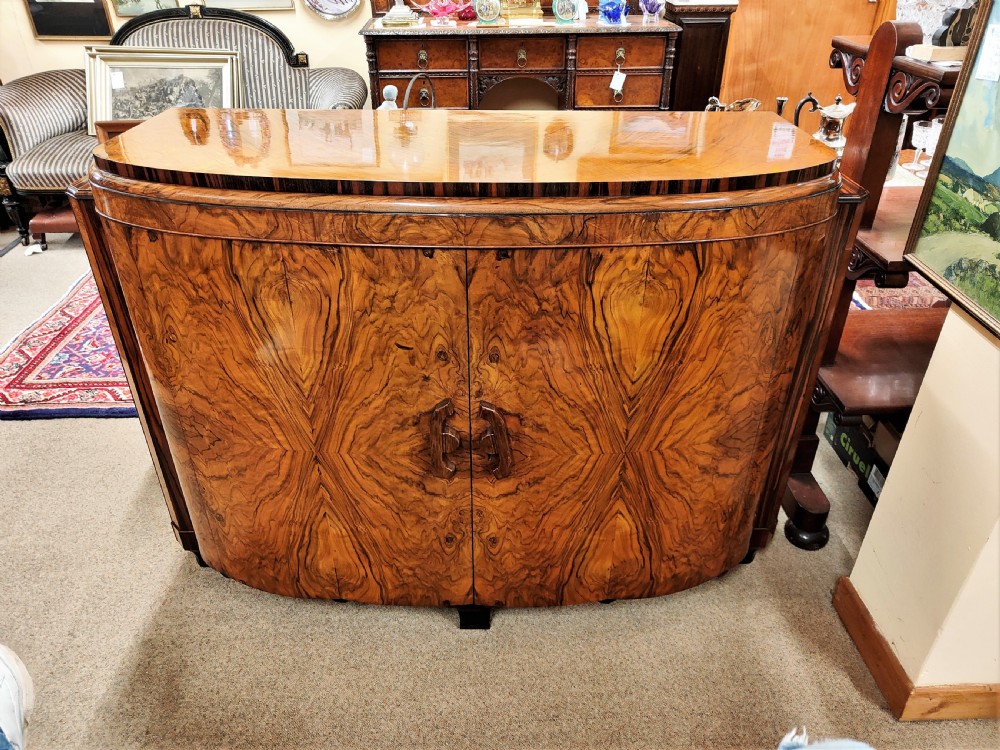A French Art Deco eleven-piece dining suite comprising an oval dining table, matching high-back chairs, and sideboards featuring heavily figured calamander and macassar ebony veneers. View V