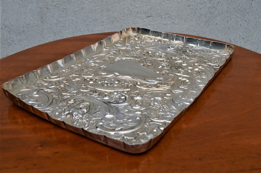 A rectangular sterling silver dressing table tray featuring detailed repousse scrollwork, foliate patterns, and a smooth central cartouche. View IV