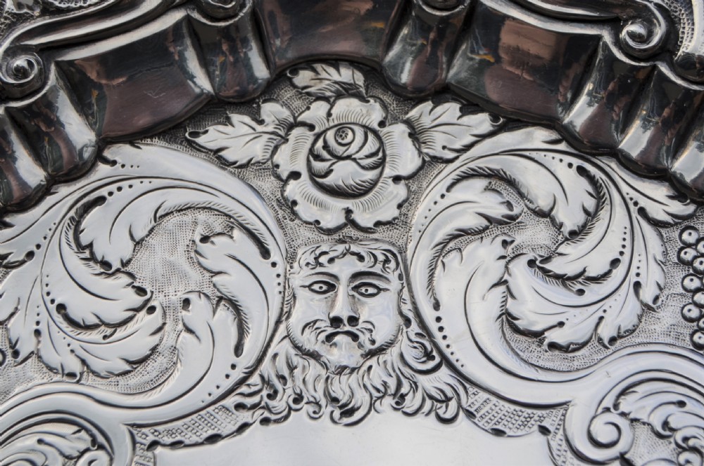 A pair of circular sterling silver salvers featuring intricate chased foliate and grapevine borders surrounding a central polished field. View III