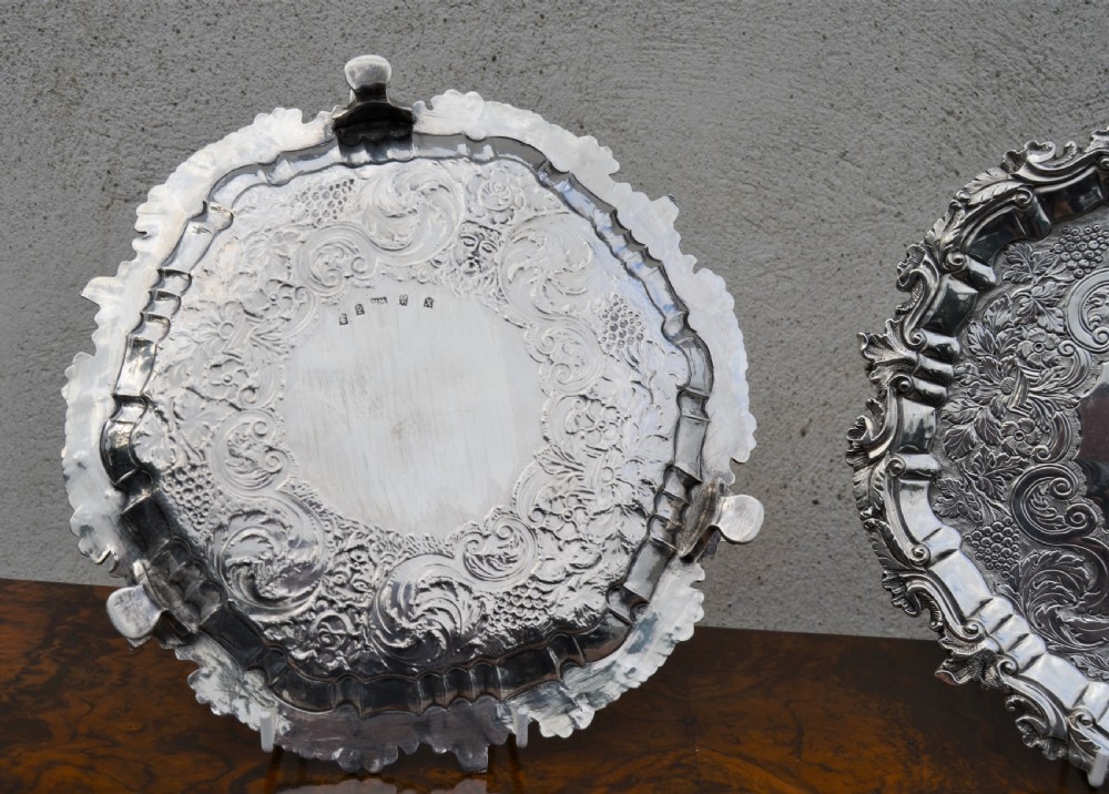 A pair of circular sterling silver salvers featuring intricate chased foliate and grapevine borders surrounding a central polished field. View IV