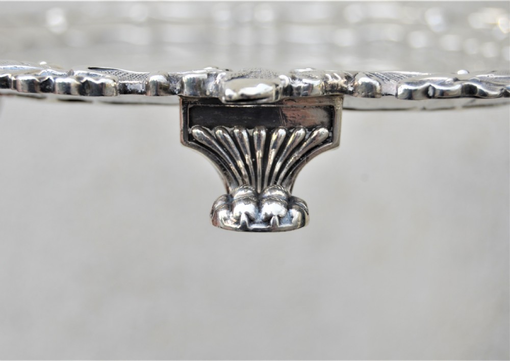 A pair of circular sterling silver salvers featuring intricate chased foliate and grapevine borders surrounding a central polished field. View IX