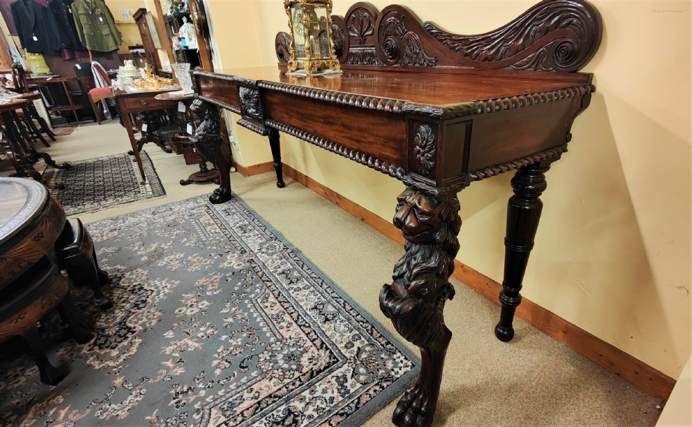 A William IV carved mahogany serving table featuring a raised carved backboard, rope-twist edging, central carved motif, and front legs with carved lion monopodia. View III