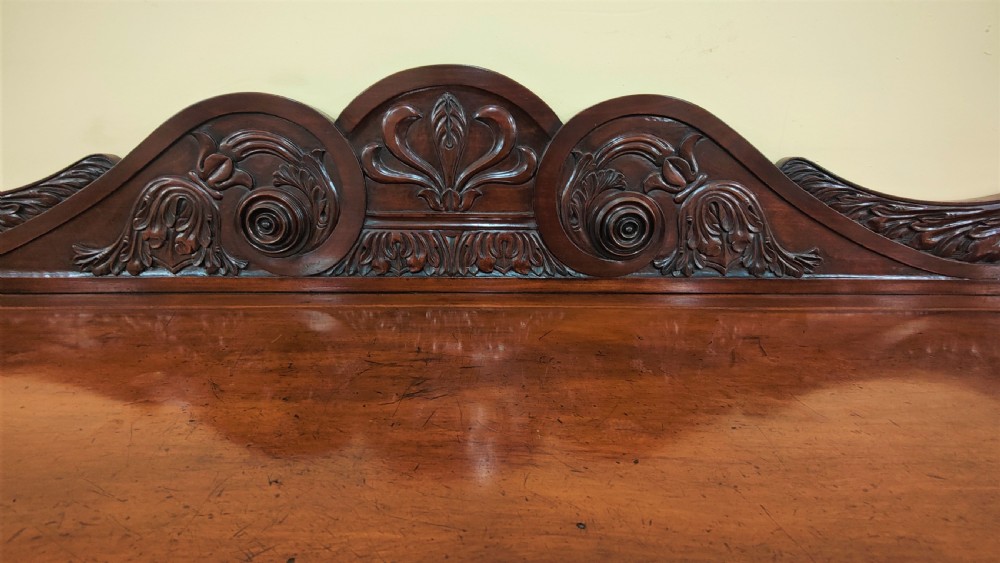 A William IV carved mahogany serving table featuring a raised carved backboard, rope-twist edging, central carved motif, and front legs with carved lion monopodia. View IV