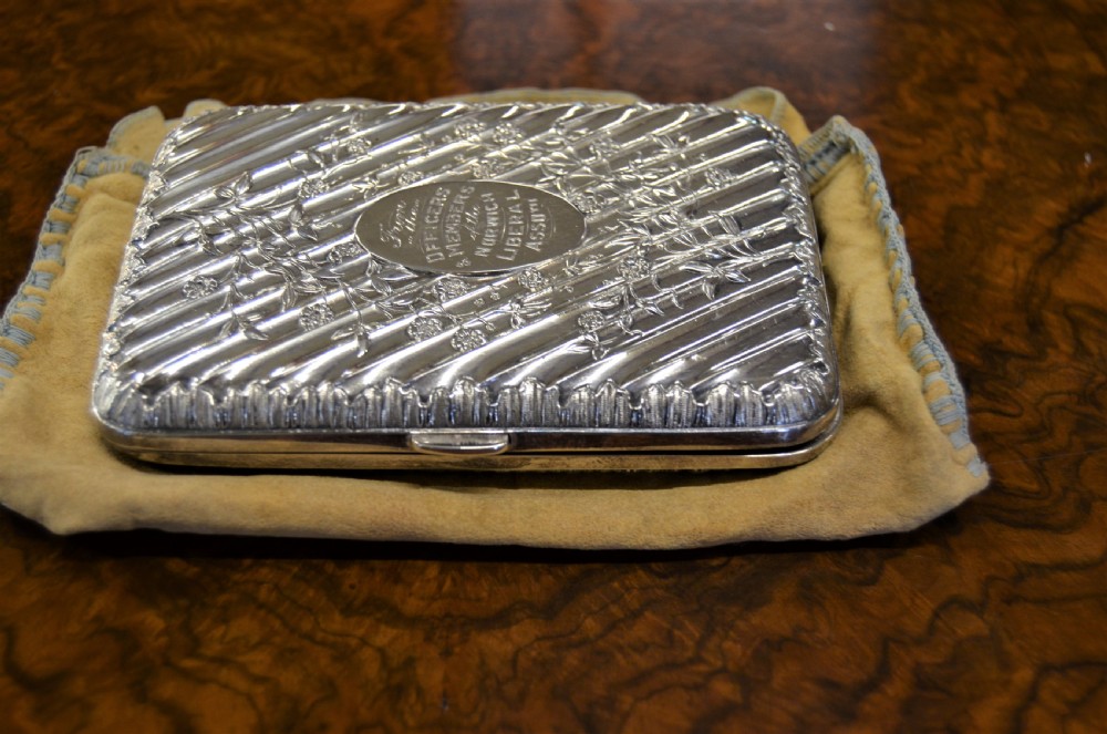 A rectangular Edwardian sterling silver cigarette case featuring diagonal fluting, chased floral motifs, and a central engraved oval cartouche. View III
