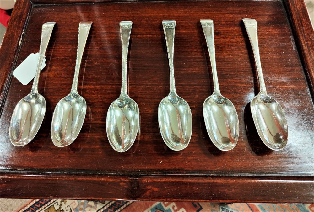 A set of six George III Irish sterling silver tablespoons in the Old English pattern, featuring bright-cut engraved edges and crests on the terminals. View II