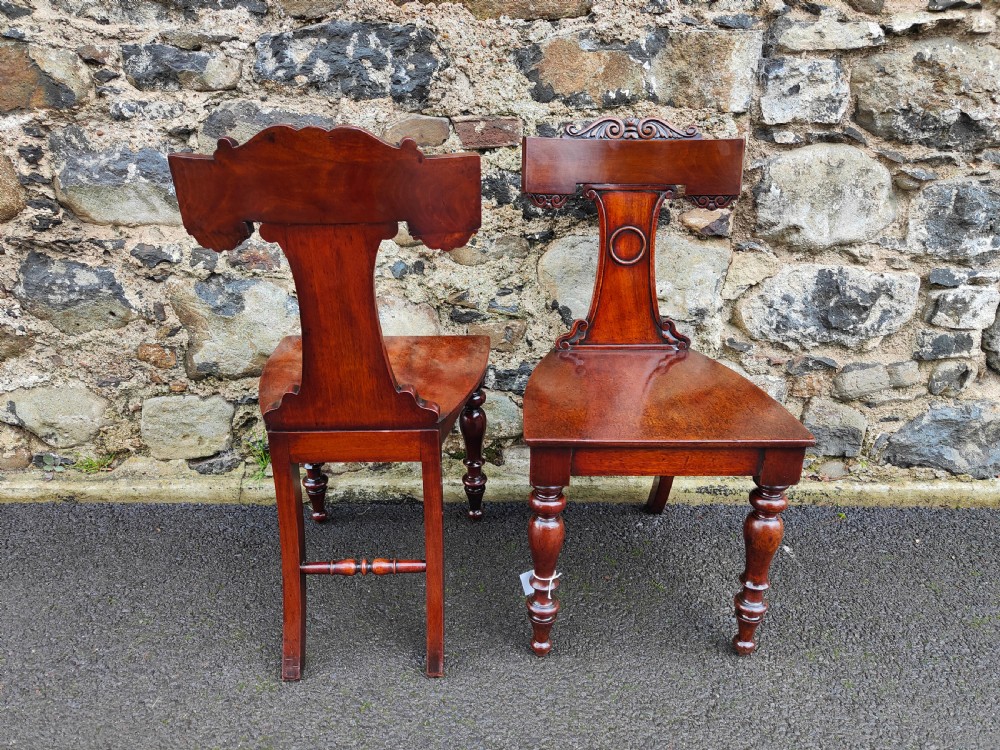 A pair of 19th-century rich brown mahogany hall chairs with carved backrests, solid seats, and turned front legs. View IV
