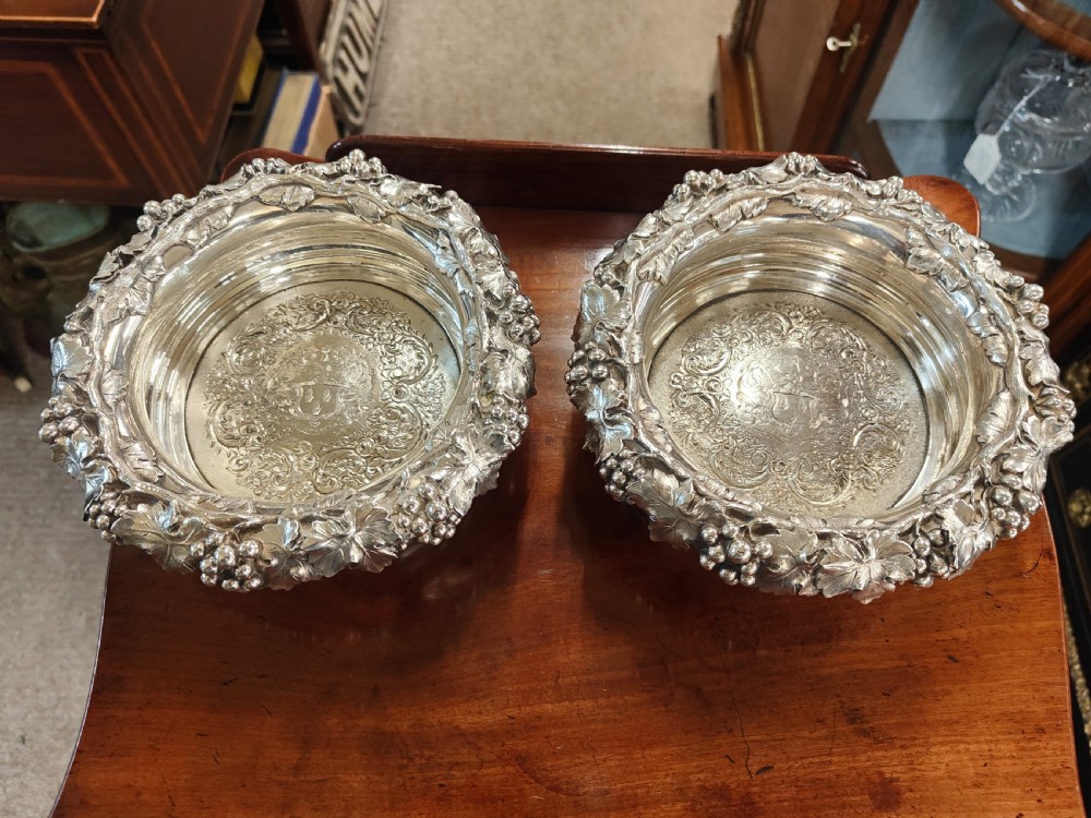 A pair of circular Georgian silver wine coasters featuring intricate cast grape and vine leaf borders with turned wooden bases. View II