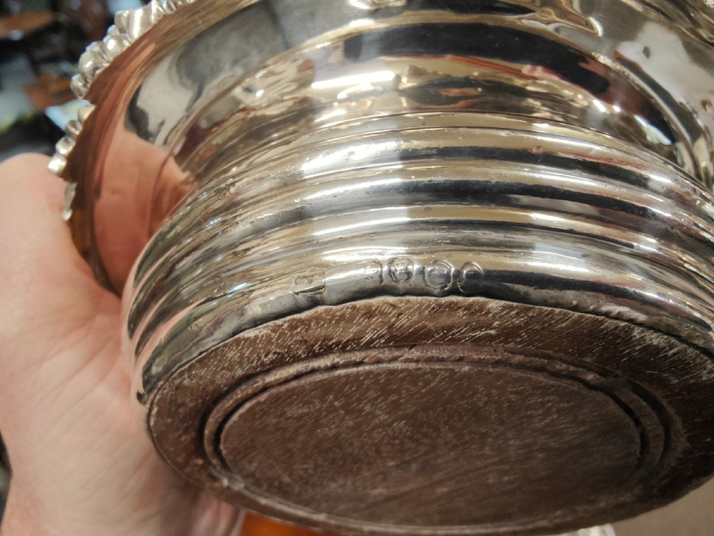 A pair of circular Georgian silver wine coasters featuring intricate cast grape and vine leaf borders with turned wooden bases. View IV