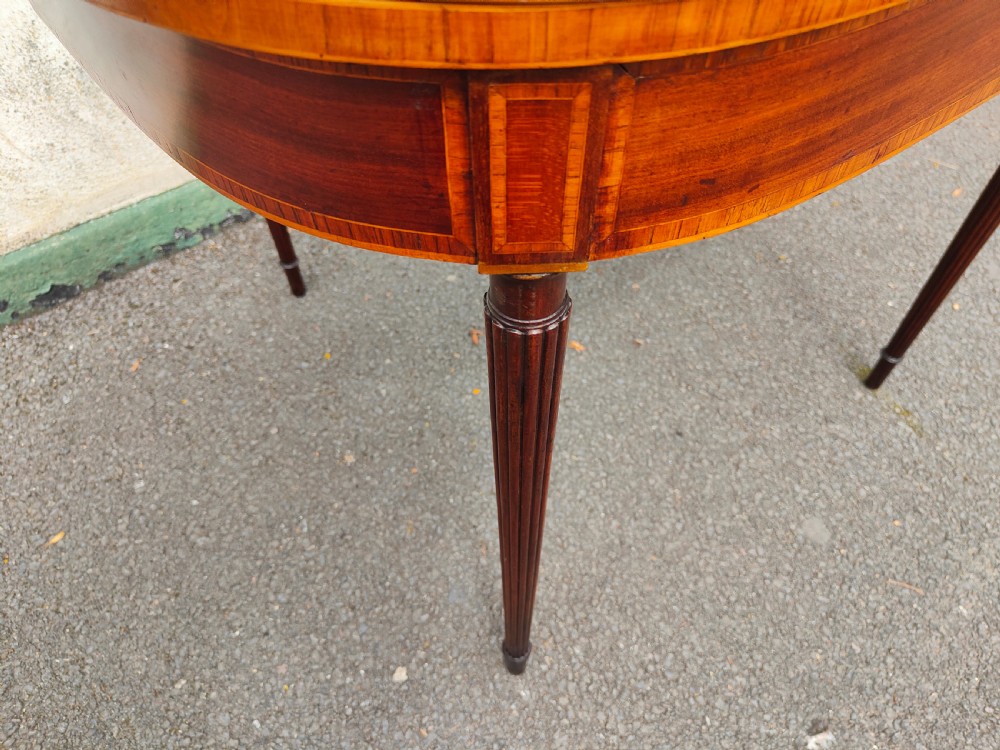A Georgian mahogany demilune card table featuring satinwood crossbanding along the folded top and fluted tapered legs. View VI