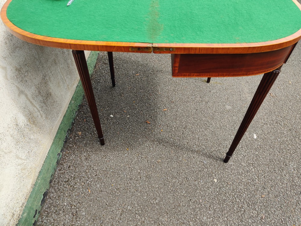 A Georgian mahogany demilune card table featuring satinwood crossbanding along the folded top and fluted tapered legs. View VII