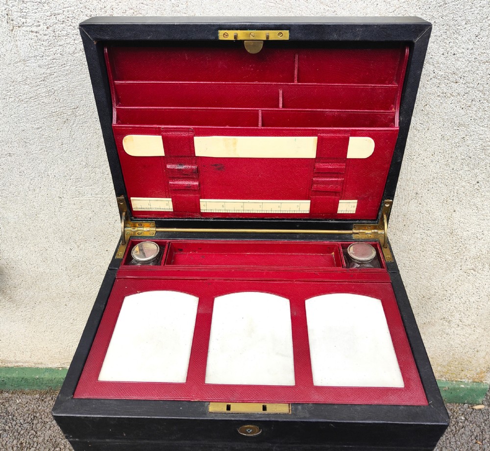 A rectangular black leather-bound writing box featuring a brass handle inset on top and a circular brass keyhole on the front. View II
