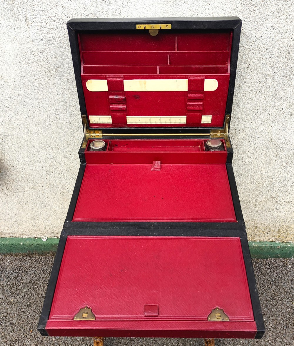 A rectangular black leather-bound writing box featuring a brass handle inset on top and a circular brass keyhole on the front. View IV