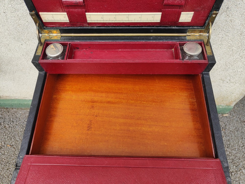 A rectangular black leather-bound writing box featuring a brass handle inset on top and a circular brass keyhole on the front. View V