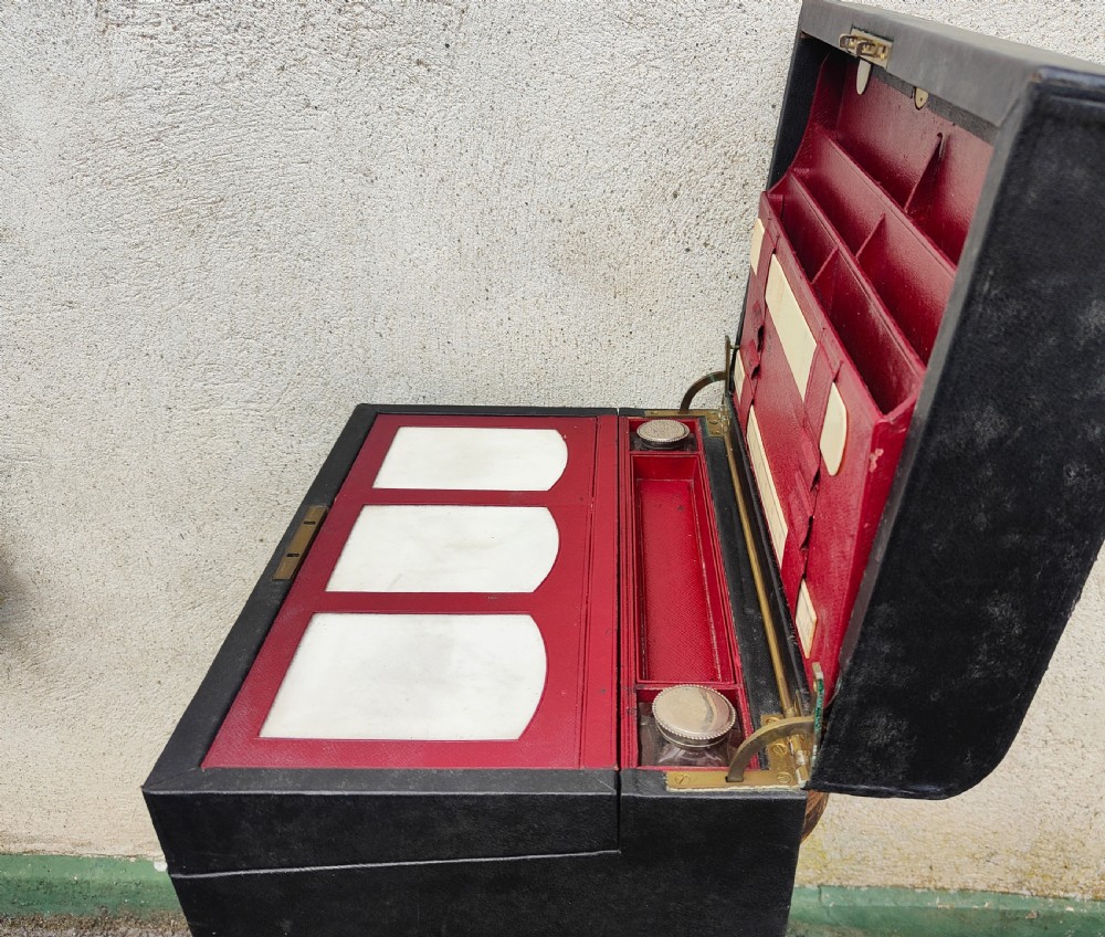 A rectangular black leather-bound writing box featuring a brass handle inset on top and a circular brass keyhole on the front. View VI