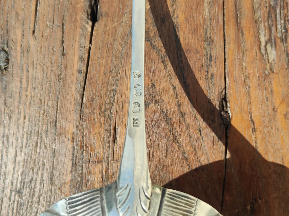 An antique sterling silver ladle featuring a detailed shell-shaped bowl and a long handle decorated with delicate bright-cut engraving. View III
