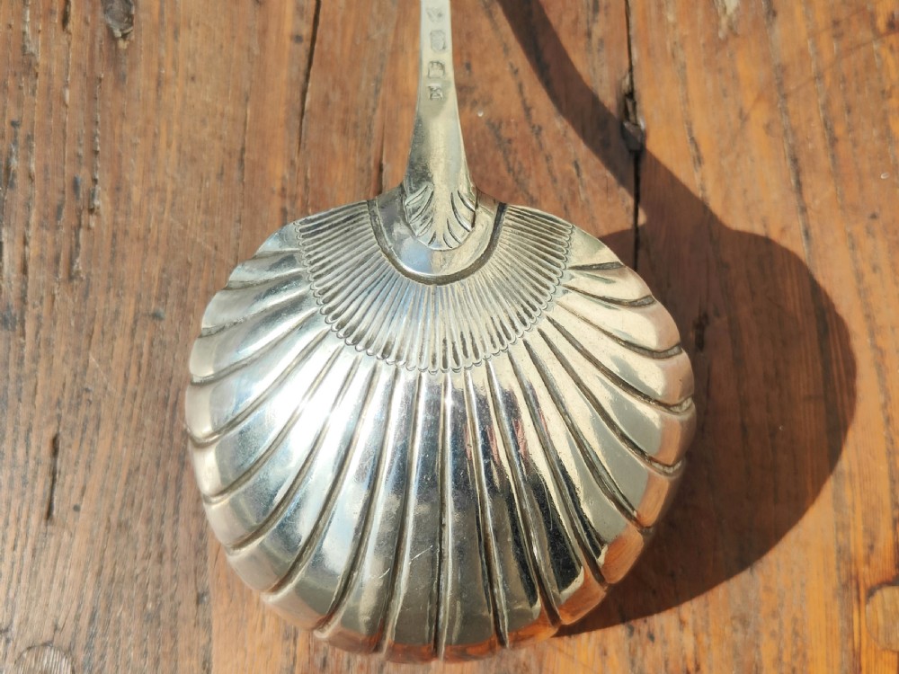 An antique sterling silver ladle featuring a detailed shell-shaped bowl and a long handle decorated with delicate bright-cut engraving. View IV