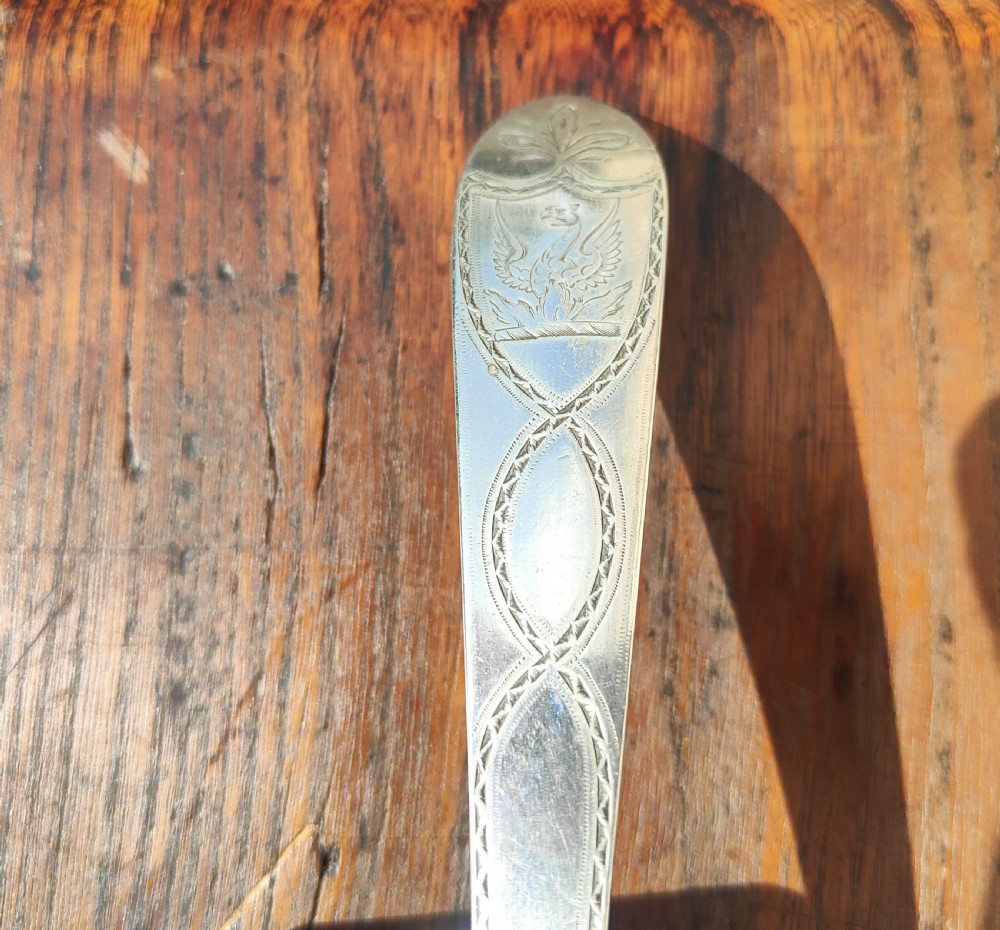 An antique sterling silver ladle featuring a detailed shell-shaped bowl and a long handle decorated with delicate bright-cut engraving. View V