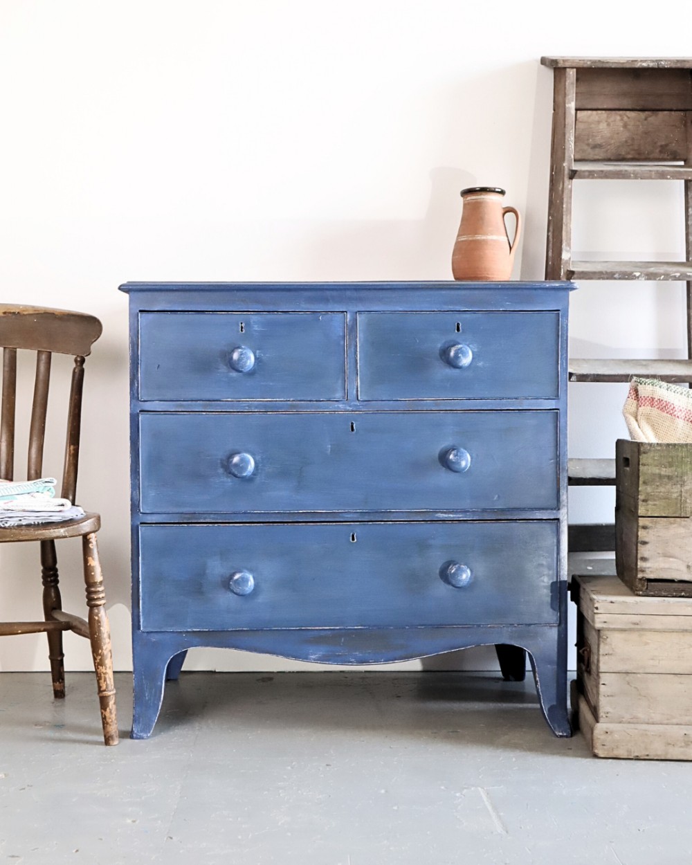 A blue painted Victorian chest of drawers featuring two short drawers over two long drawers with turned wooden knobs.