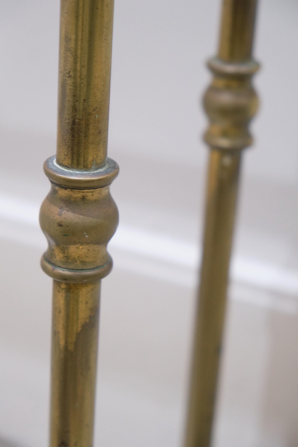 A Victorian brass umbrella stand featuring turned uprights with finials, a divided top rail, and a rectangular white drip tray base. View VI