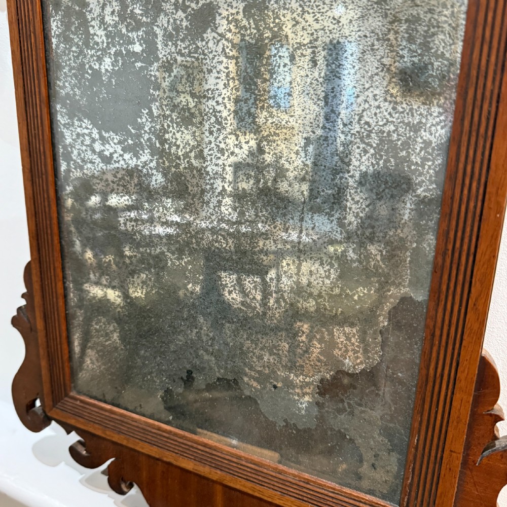 A Georgian mahogany fretwork wall mirror featuring a scrollwork cresting and heavily foxed mirror glass. View III