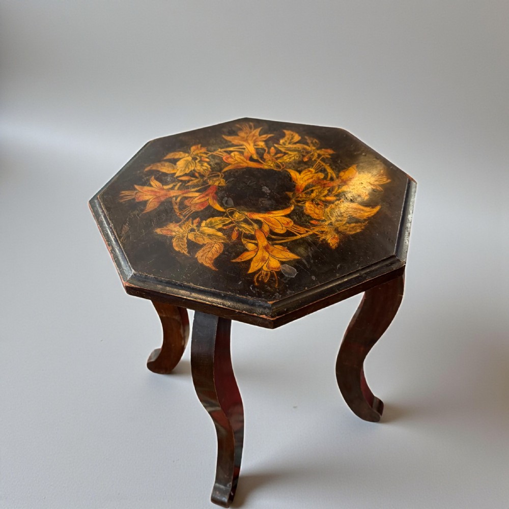 An early 20th-century octagonal side table featuring dark lacquer with intricate golden floral penwork on the top and slender cabriole legs.