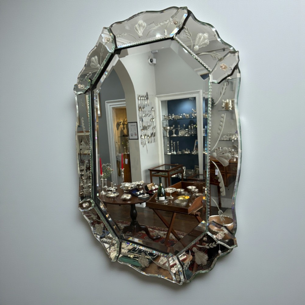 An early 20th-century octagonal Venetian wall mirror featuring an etched glass border with floral engravings, bevelled edges, and glass rosette embellishments.