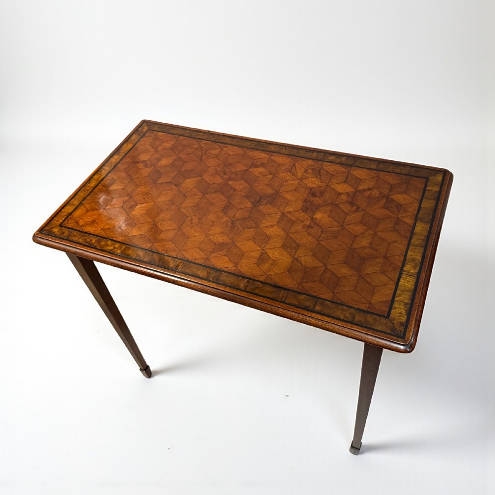 An Edwardian rectangular walnut side table featuring a geometric parquetry top with crossbanded borders and slender square tapered legs.