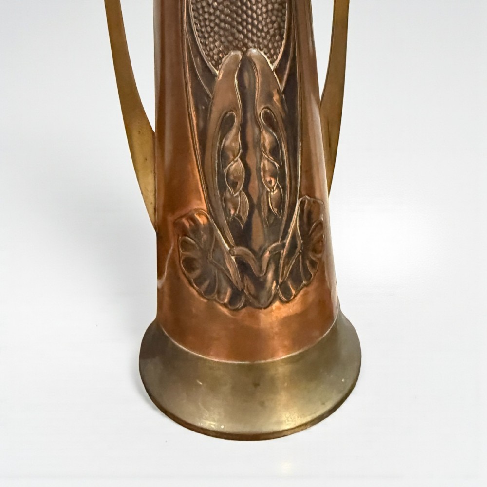 A pair of Arts and Crafts tapered copper vases featuring embossed seed pod motifs and sinuous brass handles. View II
