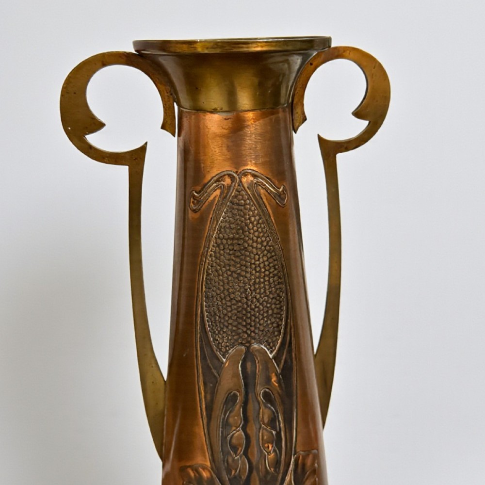 A pair of Arts and Crafts tapered copper vases featuring embossed seed pod motifs and sinuous brass handles. View III
