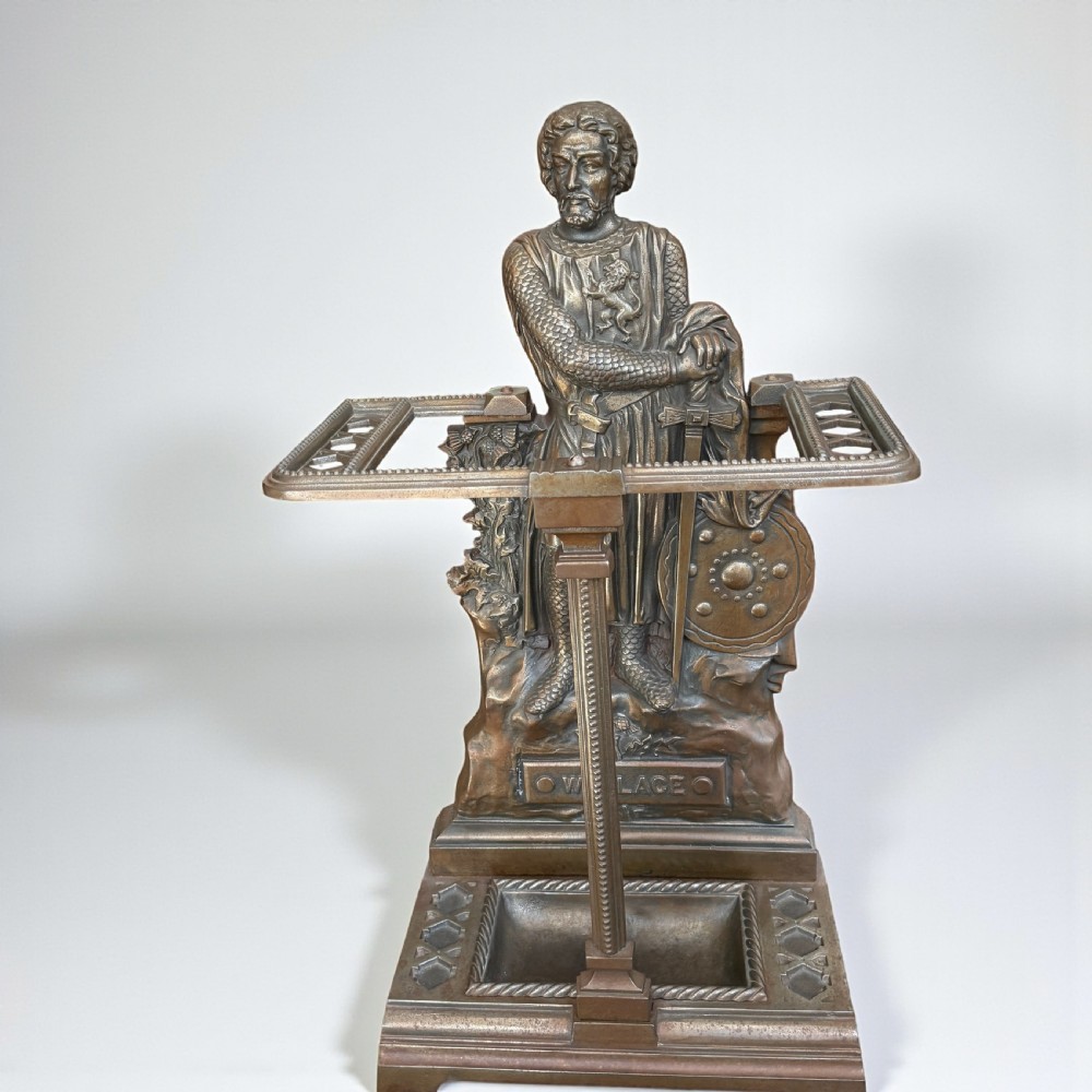 A Victorian cast iron stick stand featuring a relief figure of William Wallace in full armour with a sword, shield, upper retaining framework, and lower drip tray.