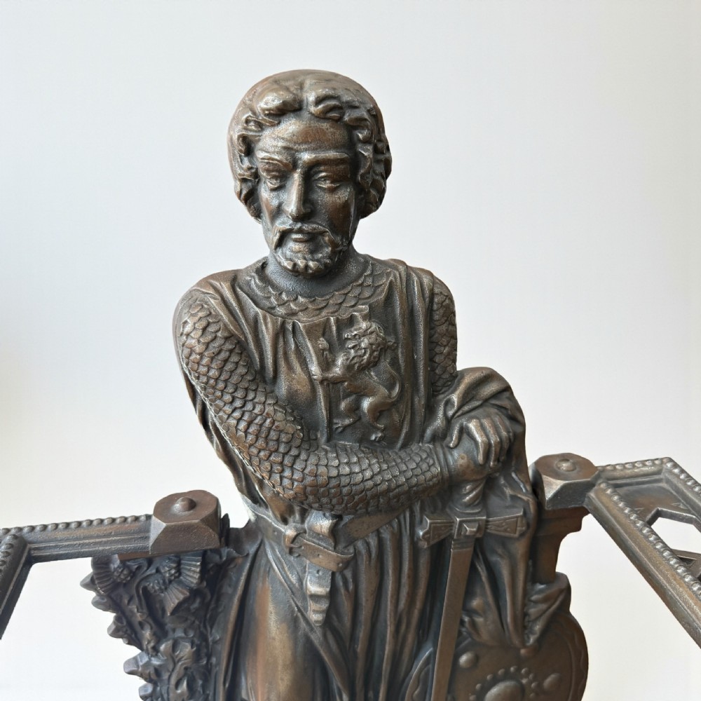 A Victorian cast iron stick stand featuring a relief figure of William Wallace in full armour with a sword, shield, upper retaining framework, and lower drip tray. View II