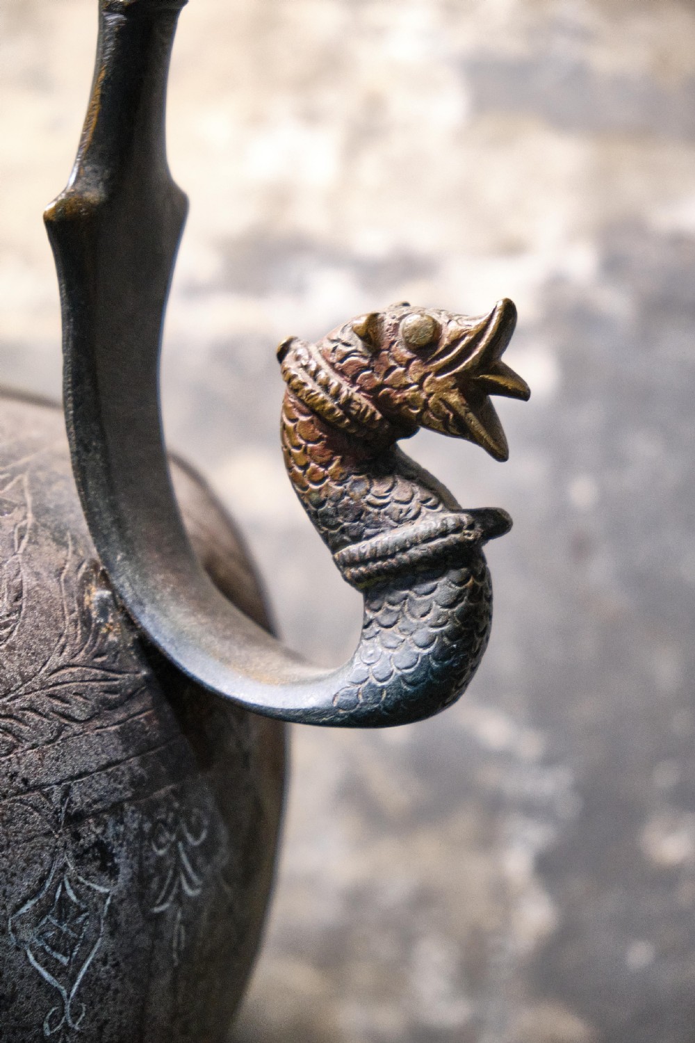 A patinated 19th-century Indian bronze ewer featuring hand-engraved floral motifs, a pedestal foot, and zoomorphic spout and handle details. View II