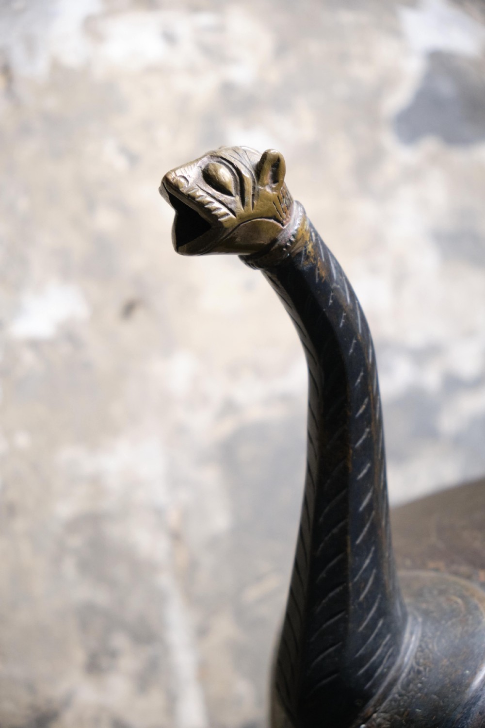 A patinated 19th-century Indian bronze ewer featuring hand-engraved floral motifs, a pedestal foot, and zoomorphic spout and handle details. View IV
