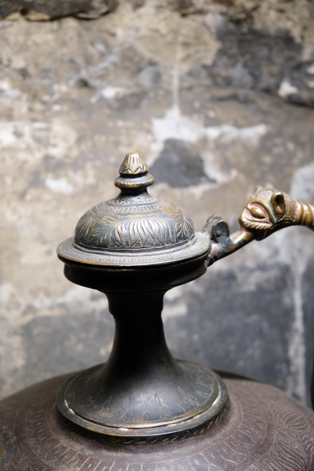 A patinated 19th-century Indian bronze ewer featuring hand-engraved floral motifs, a pedestal foot, and zoomorphic spout and handle details. View V