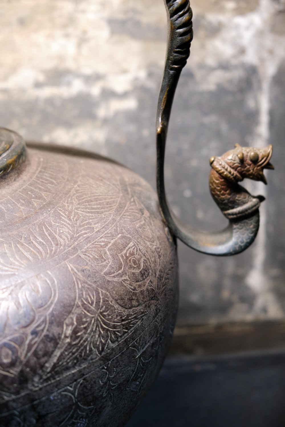A patinated 19th-century Indian bronze ewer featuring hand-engraved floral motifs, a pedestal foot, and zoomorphic spout and handle details. View VI