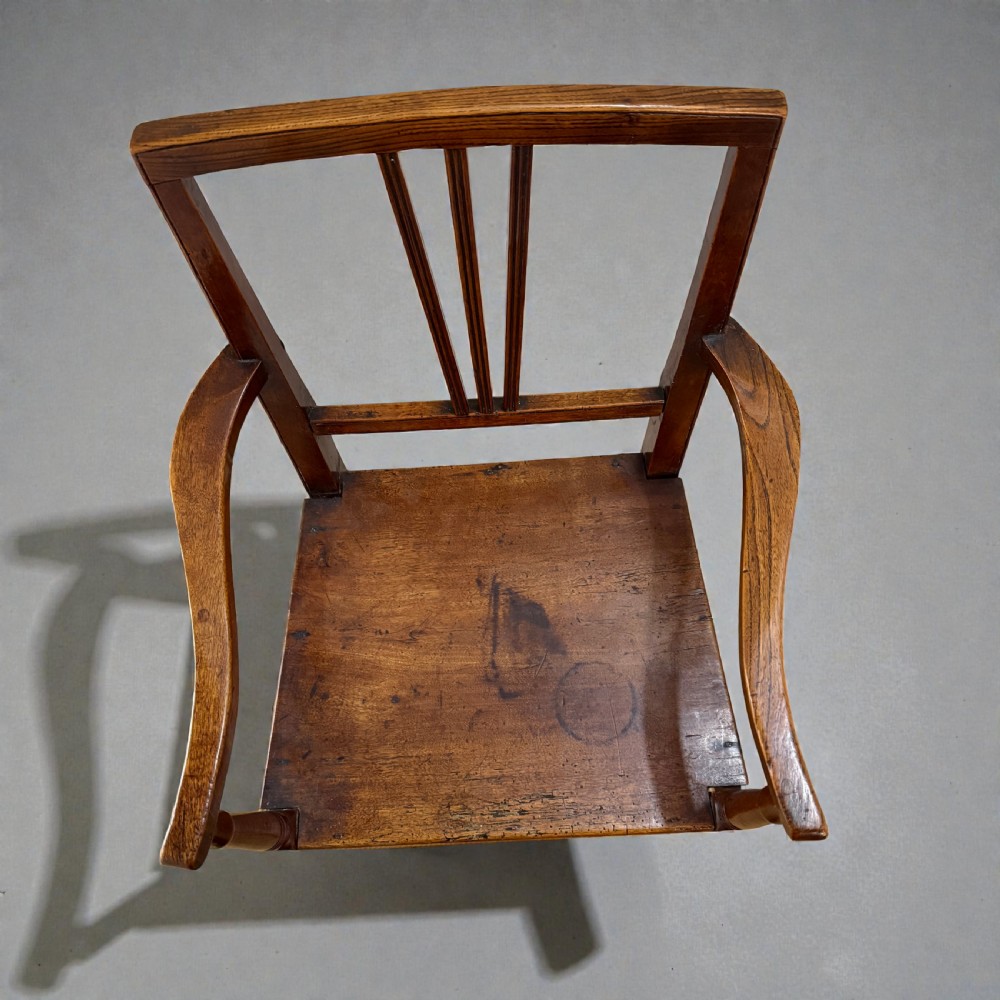 A Regency period wooden childrens high chair featuring a three-slat backrest, raised armrests with turned supports, and tall legs connected by stretchers. View III