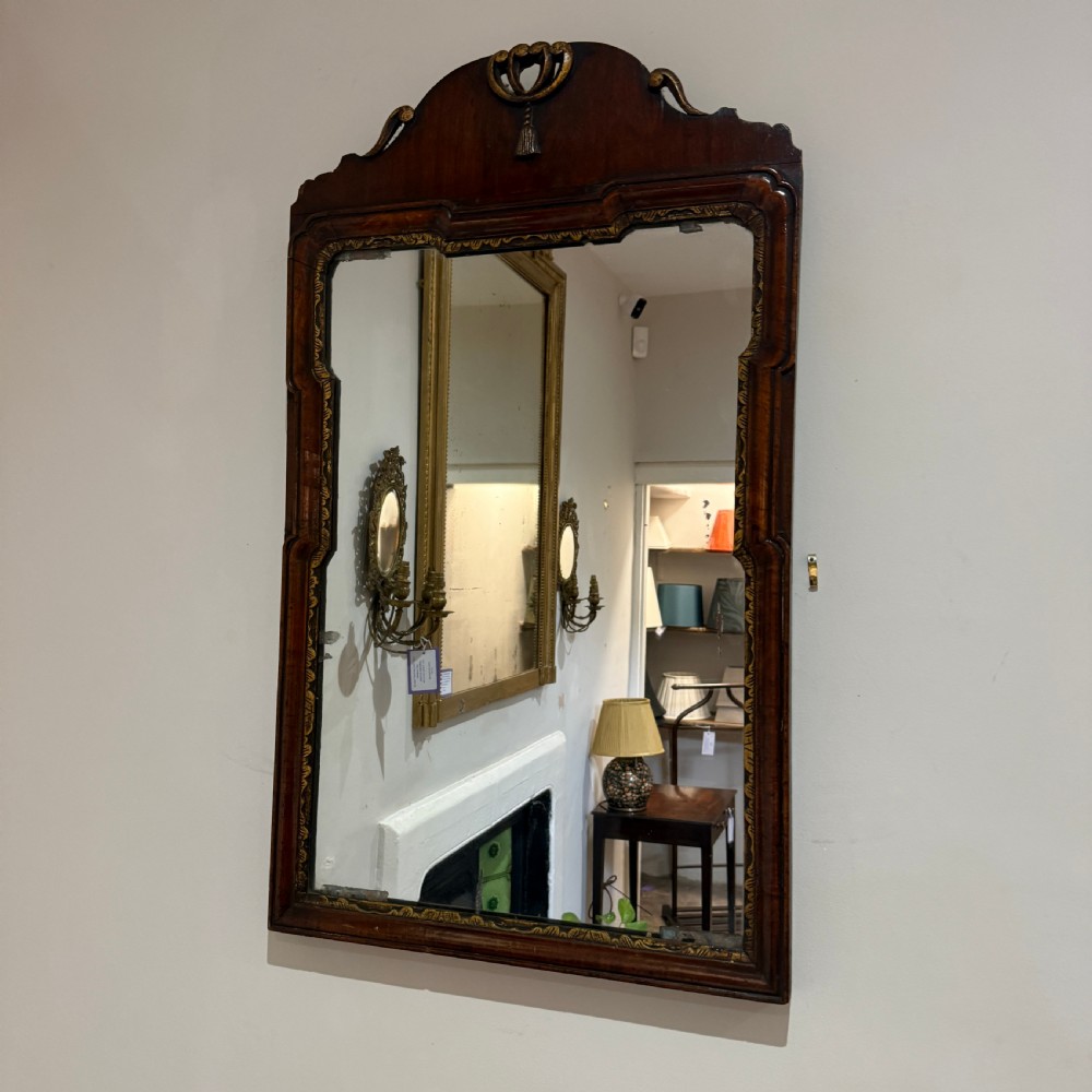 A dark mahogany wall mirror with carved fretwork scroll edging, a shaped pediment top, and a gild slip border around the reflective glass.