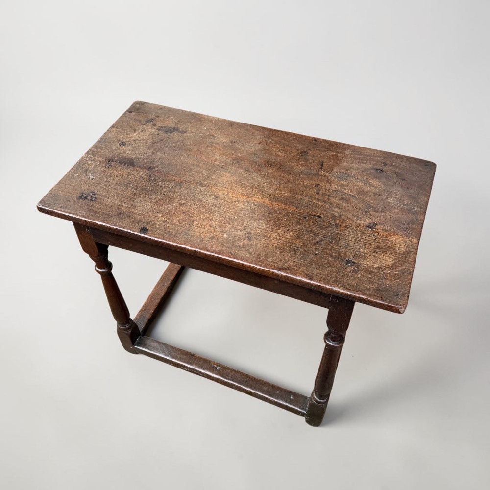A 17th-century dark oak joint stool featuring turned legs, pegged mortise and tenon construction, and a rectangular top over low perimeter box stretchers. View II