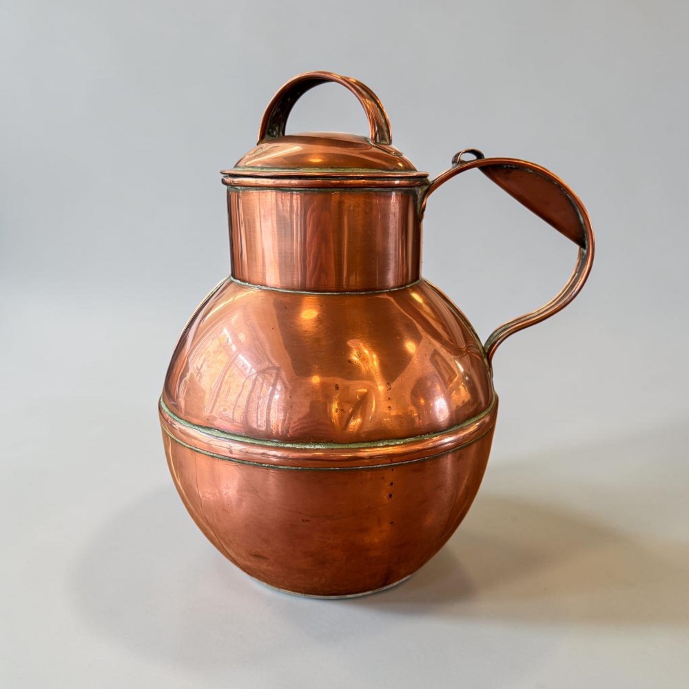 A pair of round copper Jersey milk jugs featuring fitted lids with top loop handles and wide pouring spouts. View II