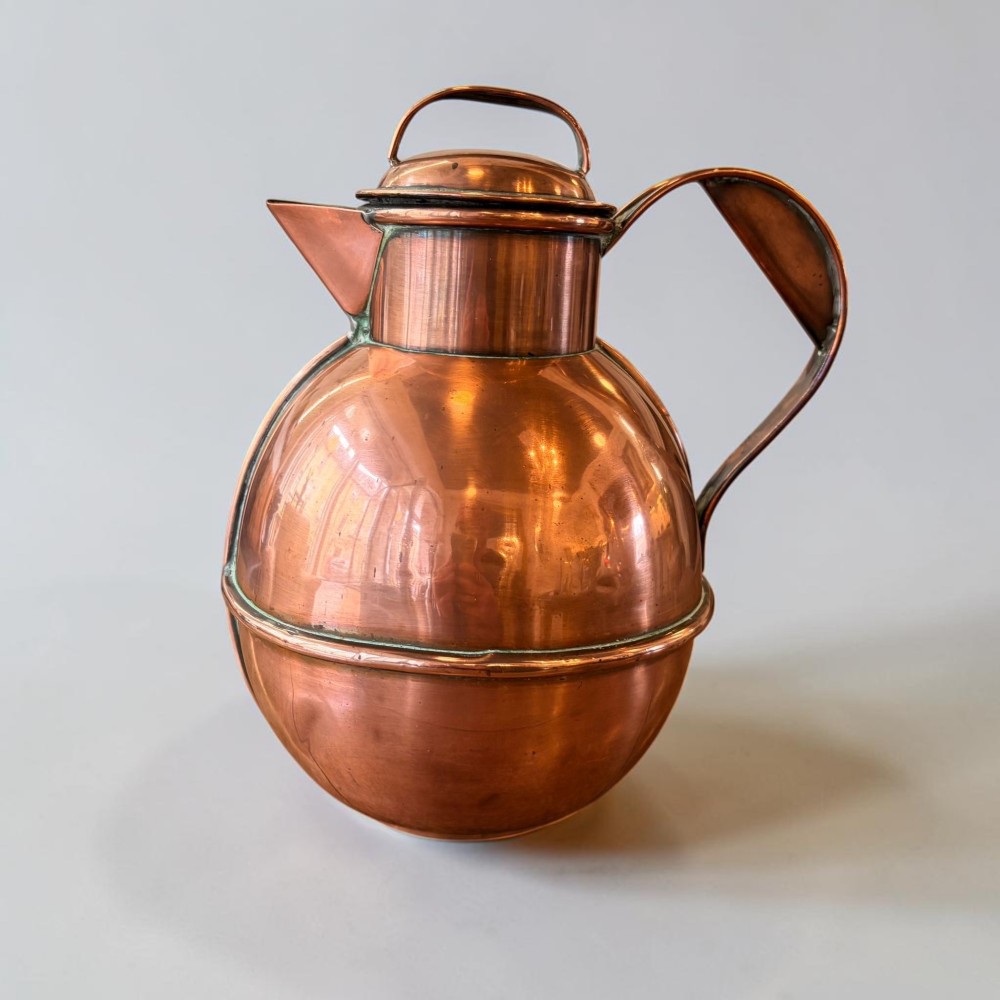 A pair of round copper Jersey milk jugs featuring fitted lids with top loop handles and wide pouring spouts. View III