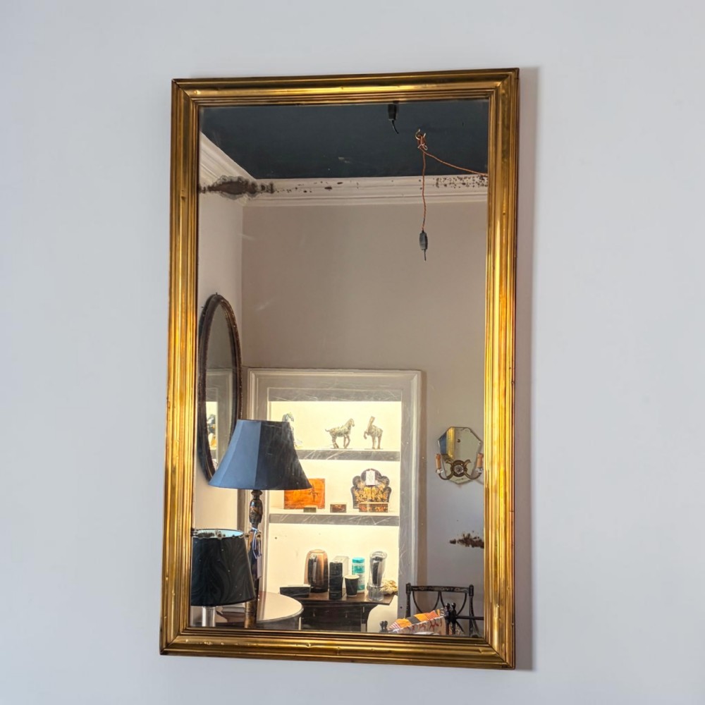 A large rectangular wall mirror featuring a gilded moulded frame with visible foxing to the silvered glass plate.