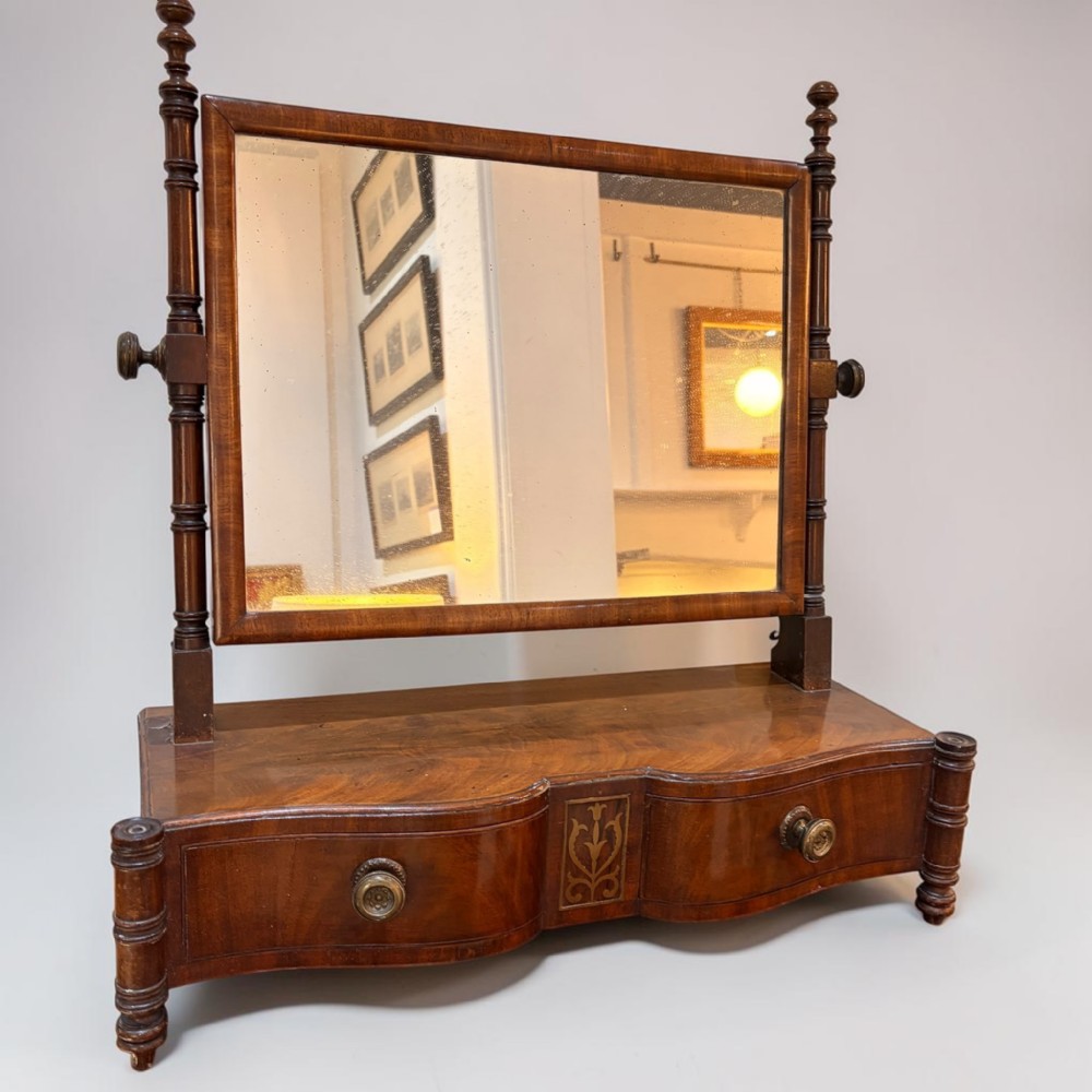 A Regency mahogany dressing table mirror with an adjustable rectangular glass frame set above a shaped base with two drawers.