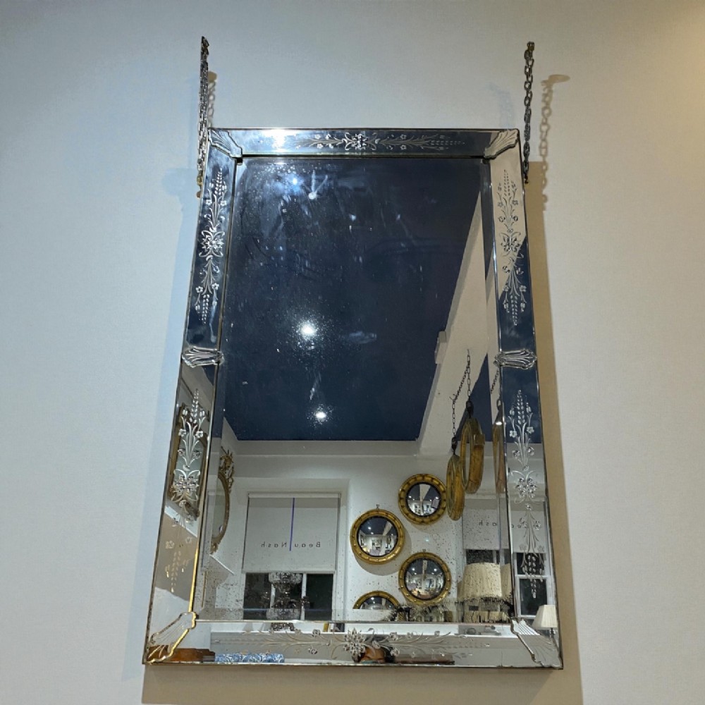 A large rectangular Venetian mirror featuring an etched floral glass border suspended from metal hanging chains.
