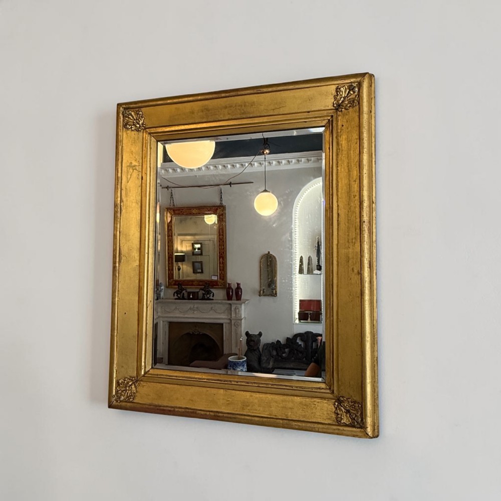A rectangular Regency giltwood wall mirror featuring carved corner ornaments and a bevelled glass plate.
