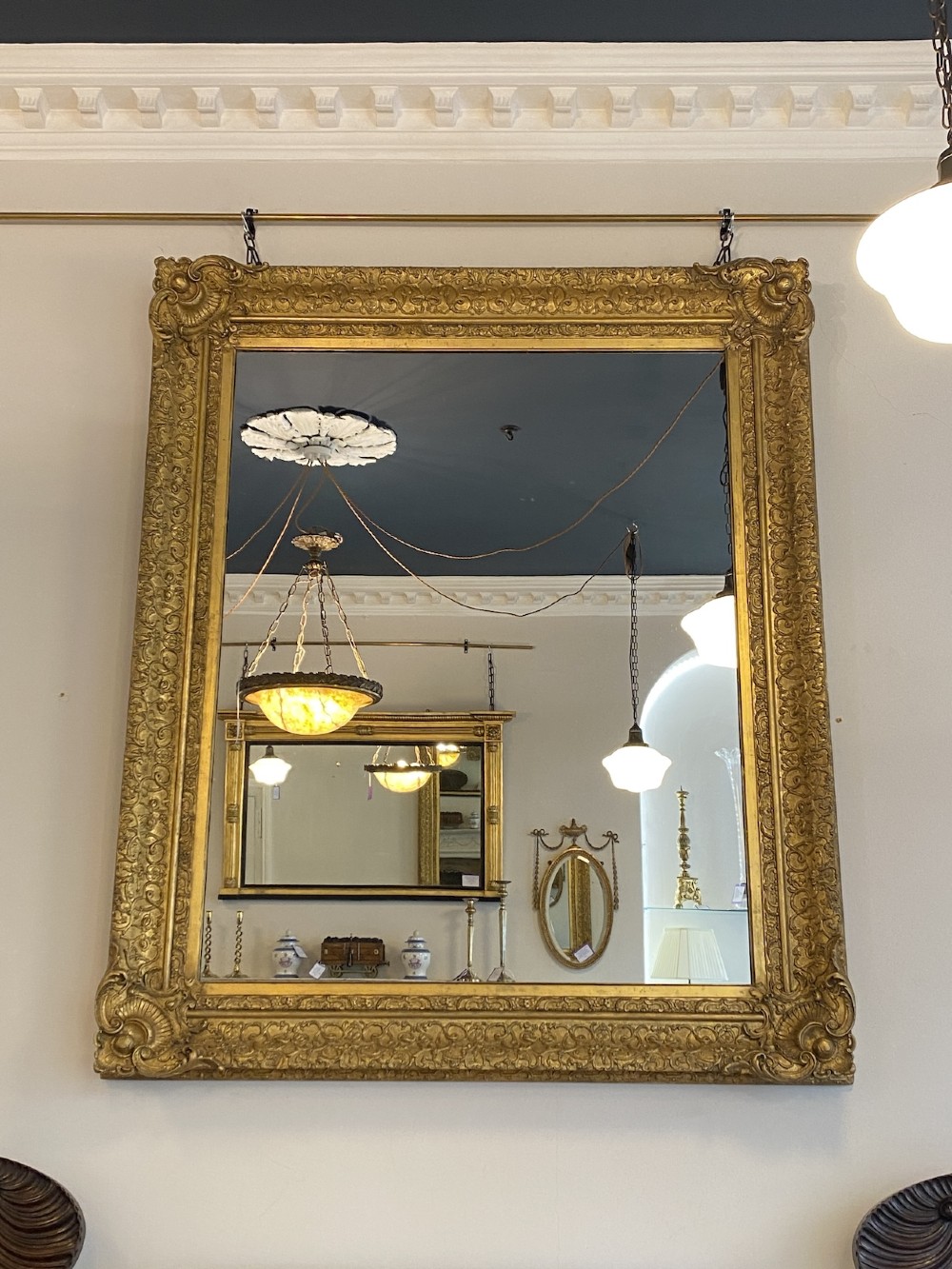 A large rectangular 19th-century wall mirror featuring an ornate gilded frame with carved acanthus leaf corner mouldings.